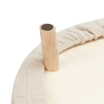 Detailaufnahme eines runden Holzgestells mit beigem Stoffbezug und einer vertikalen Holzstange.
