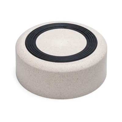 Socle rond beige avec un anneau noir en relief sur le dessus, matériau ressemblant à du plastique ou composite, sans marque ni texte visible.