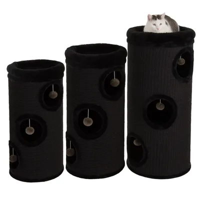 Three black cylindrical cat towers of different heights, each with multiple entry holes and hanging ball toys. A cat is sitting in the top opening of the tallest tower.