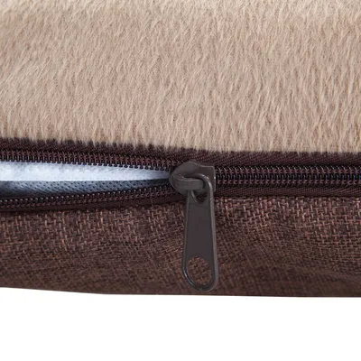 Gros plan sur une fermeture éclair marron sur un coussin pour animaux, avec dessus en tissu beige effet fourrure et dessous en tissu tissé brun. Matériaux visibles : tissu, plastique.