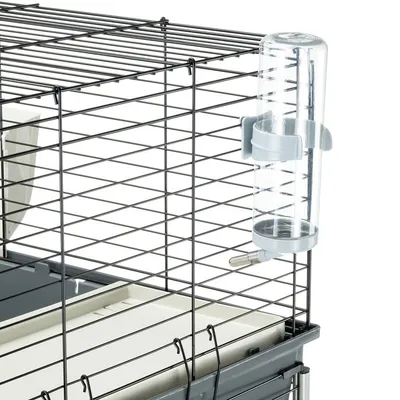 Käfig aus Metall mit Gitterwänden, ausgestattet mit einer transparenten Trinkflasche und grauer Halterung.