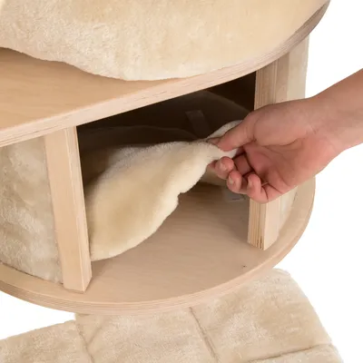 Ръка повдига подвижна, бежова плюшена възглавница от дървена платформа на мебел. Показва лесно почистване или подмяна на възглавницата.