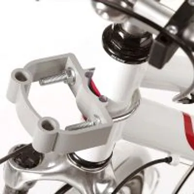 Soporte de plástico gris con tornillos montado en el manillar de una bicicleta blanca con detalles rojos, visible parte del cableado y la horquilla.