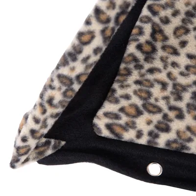 Vista detallada de una manta con estampado de leopardo y reverso negro, ojal metálico visible.