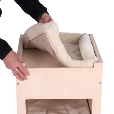 Puinen runko irrotettavalla beigellä tyynyllä. Käsi nostaa tyynyä toiminnon esittelemiseksi.