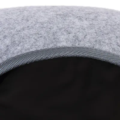 Detaljvy av grått filtmaterial med svart insida och förstärkt kant av vävt tyg.