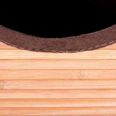 Détail d’un rebord en tissu marron sur une surface en bois clair à lattes horizontales, sans autres éléments visibles.