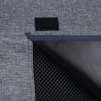 Detailansicht eines grauen Stoffmaterials mit Klettverschluss und schwarzem Netzgewebe darunter.