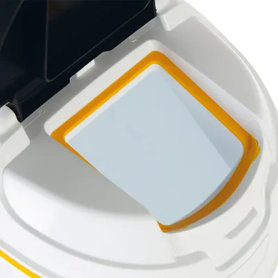 Detalle de tapa con borde amarillo y ventana transparente en recipiente blanco, material plástico visible. No se muestra marca ni texto.