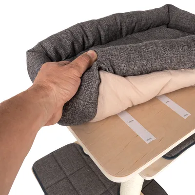 Hand zeigt abnehmbares, gepolstertes Kissen mit Klettverschluss auf einer Holzplattform.