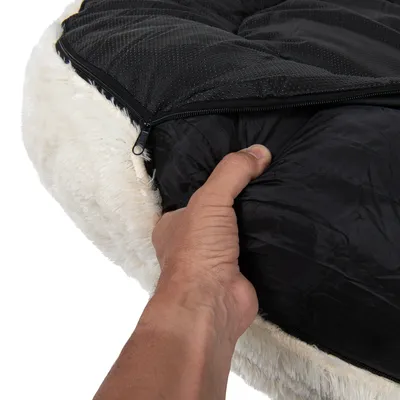 Hand demonstrating removable inner cushion with zip opening on a soft, round bed. Shows how to access or remove the inner padding for cleaning or adjustment.