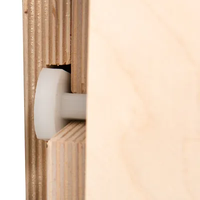 Detailní pohled na dřevěný spoj s plastovým válečkem, ukazuje přesné zpracování a kombinaci dřeva a plastu.