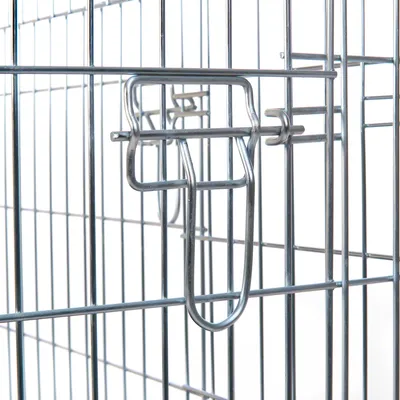 Metallinen koiranhäkin ovi ja lukitusmekanismi, hopeanväristä metallia. Yksityiskohta häkin rakenteesta.
