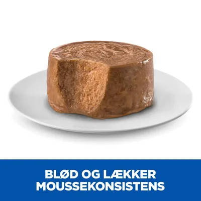 Blød og lækker mousse konsistens, tekst synlig: BLØD OG LÆKKER MOUSSEKONSISTENS. Viser brun mousse på hvid tallerken med en bid taget af.