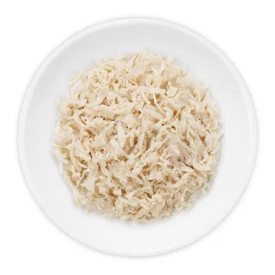 Wit schaaltje met fijn gesneden, lichtgekleurde stukjes natvoer voor huisdieren, zonder zichtbare merknaam of verpakking.