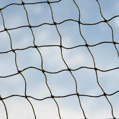 Nahaufnahme eines stabilen Netzes aus geflochtenem Seil vor blauem Himmel, geeignet für Schutz- oder Abgrenzungszwecke.