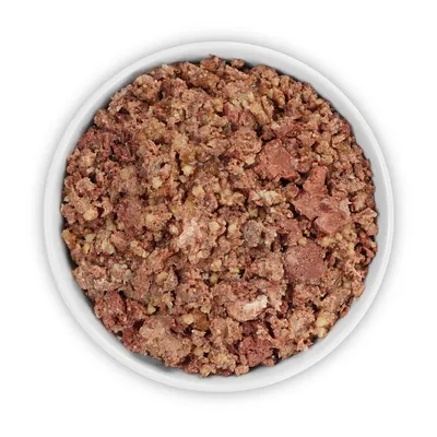 Nourriture humide pour animaux présentée dans une gamelle blanche, mélange de morceaux bruns et beiges à texture hachée, sans marque ni texte visible.